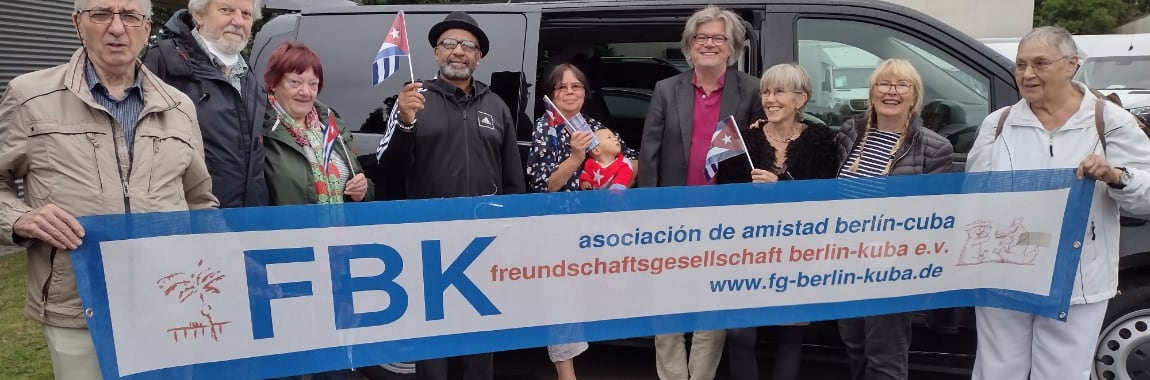 Gruppenfoto mit Banner der Freundschaftsgesellschaft Berlin-Kuba vor dem mit Spendengeldern gekauften Mercedes Vito